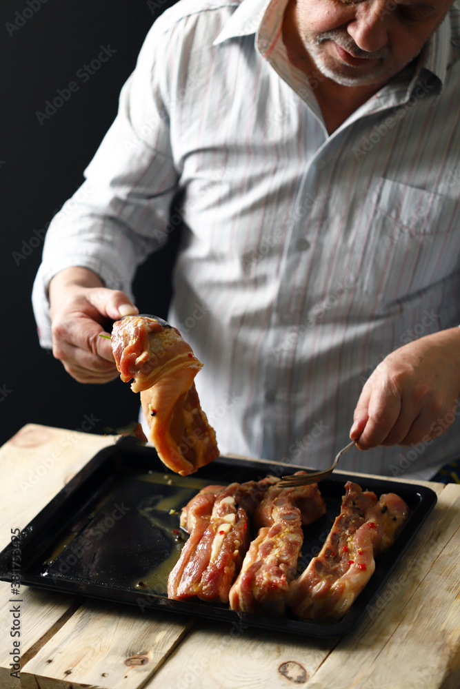 Selective focus. The chef puts the marinated pork ribs on a baking sheet. Barbecuing ribs.