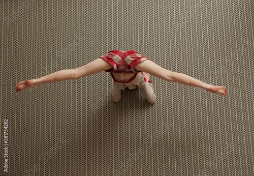 young teen girl wearing casual clothes working out in studio. Fit yogi girl doing advanced inversion and arm-balance. Handstand. Vrischikasana. Full length. top view image photo