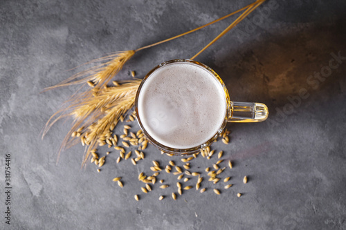 Glass of light beer and barley on a gray background, flat lay.