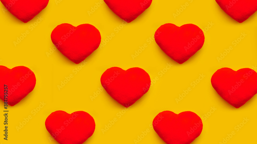 Rows of red heart toys on yellow background. Top view. Flat lay