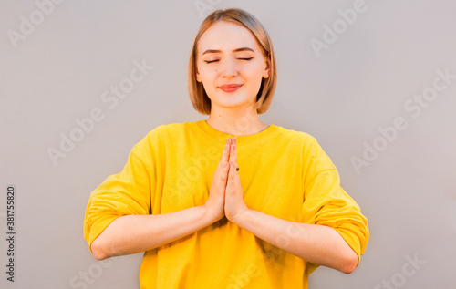 Namaste peace your house. Relaxed peaceful charming friendly european girl press palms together buddhism gesture smiling cute thanking dear guest hold hands pray standing gray background