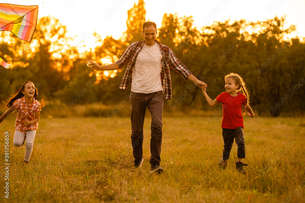 Fototapeta premium Dad with his little daughter let a kite in a field