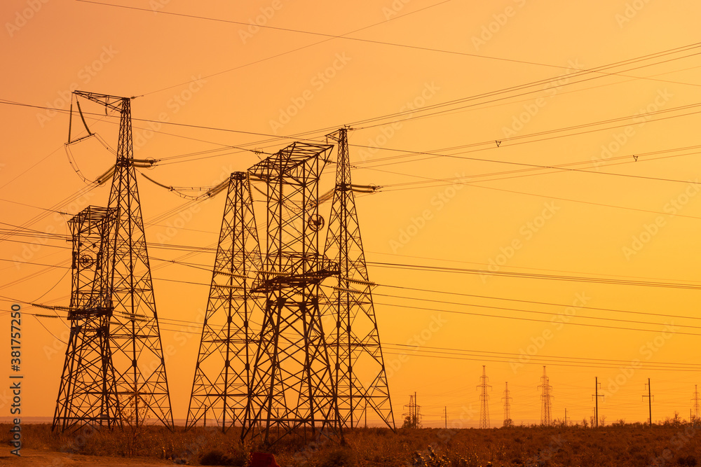 High voltage power lines, iron towers, bright orange background.