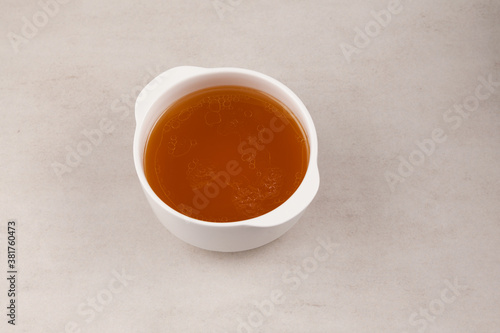 Beef bone broth in white bowl on a stone surface. Healthy beverage with natural collagen. Selective focus, copy space