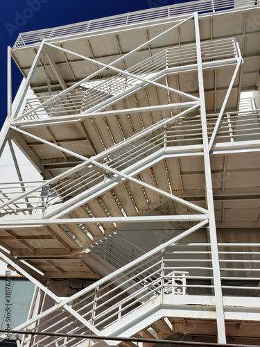 Metal exit stair on the facade of a multistory modern building of sandwich panels. Vertical view  look up.