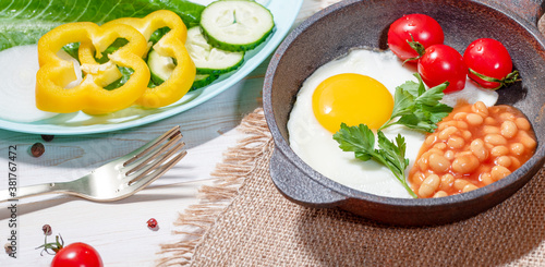 Fried egg in cast iron serving pan, cherry tomatoes, beans and vegetables