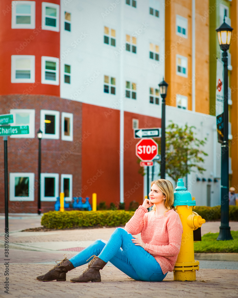 A thoughtful student girl sitting on the city street under the One Way and Stop sign, decision making concept