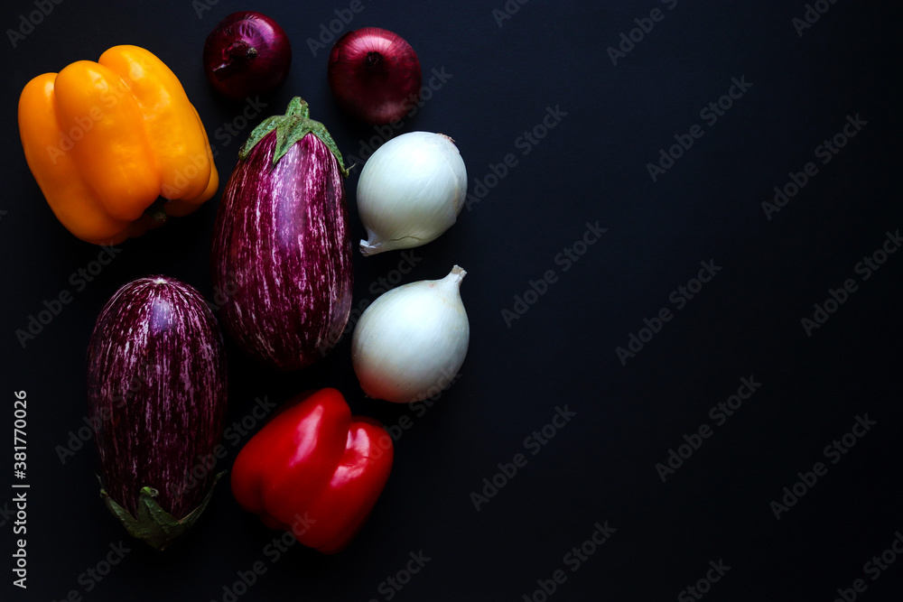 Harvest concept. Raw vegetables: eggplants, sweet pepers and onions on a dark background. Selective focus, close-up, top view. Copy space. Food background Harvest concept. Raw vegetables: eggplants, sweet pepers and onions on a dark background. Selective focus, close-up, top view. Copy space. Food background