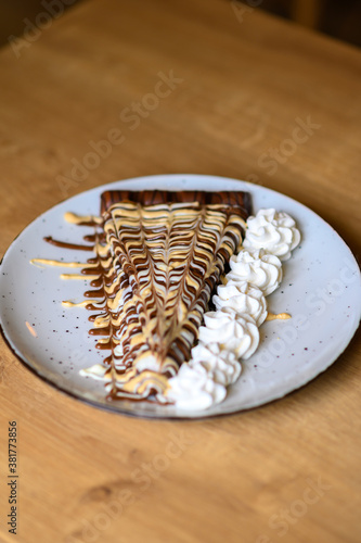 a beautifully decorated caloric pancake full of chocolate.
pancake on a red plate with lots of whipped cream.