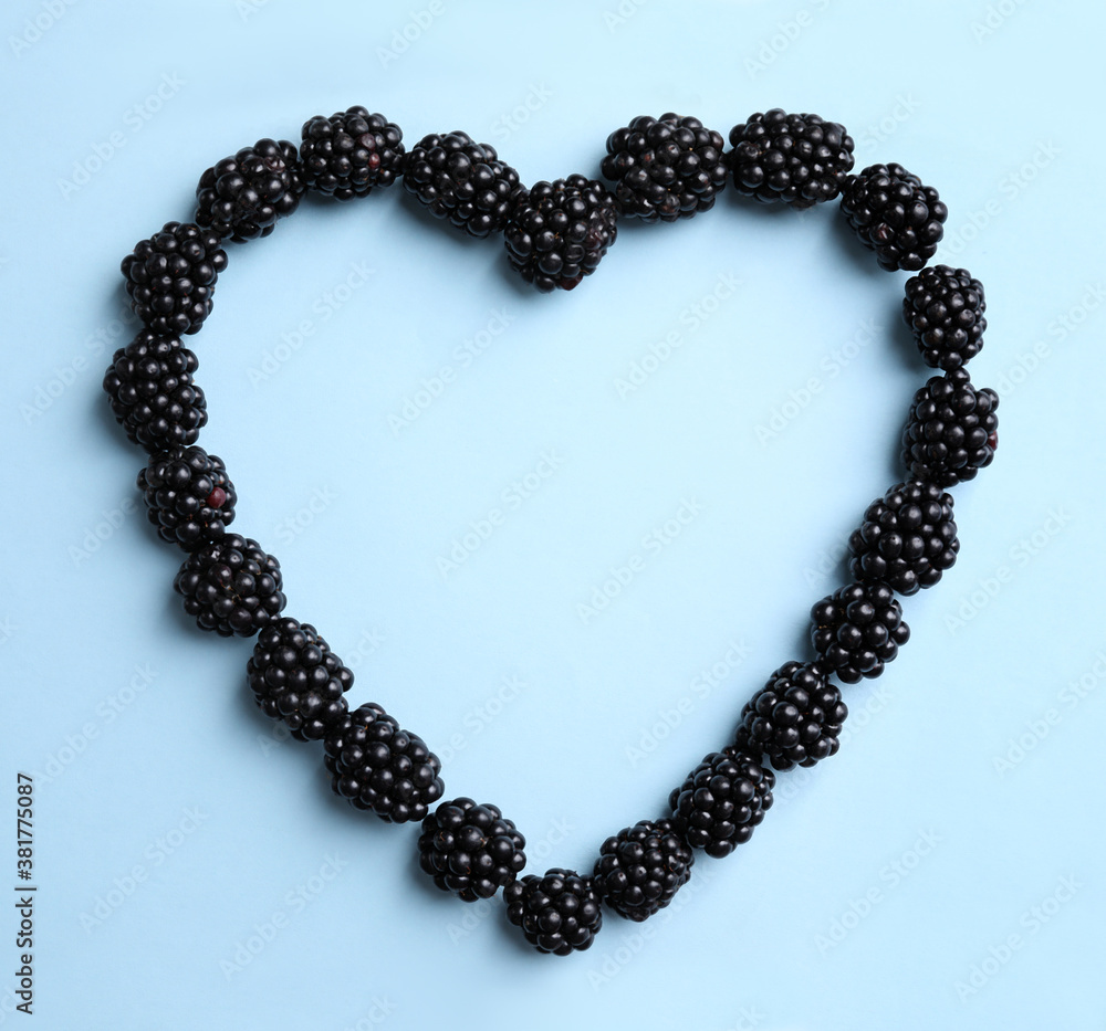 Heart shaped frame of ripe blackberries on light blue background, flat lay. Space for text Heart shaped frame of ripe blackberries on light blue background, flat lay. Space for text