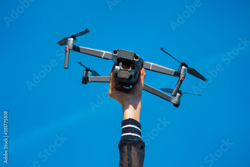 Woman holding drone or quadcopter isolated on the blue sky background. Flying drone outside in summer.