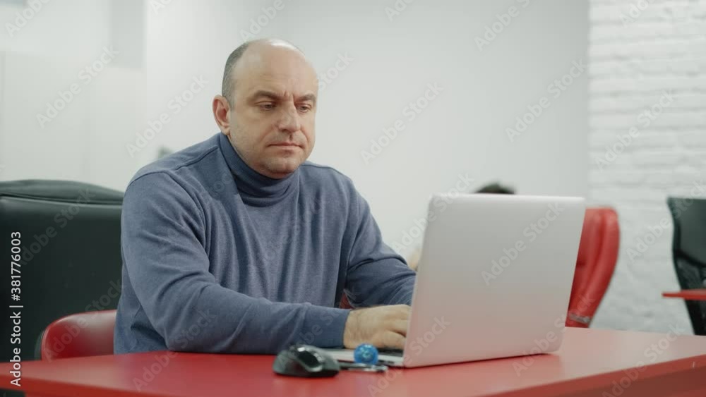 Mature programmer man is working on laptop in the office Mature programmer man is working on laptop in the office