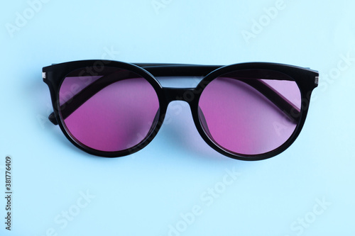 Stylish sunglasses on light blue background, top view