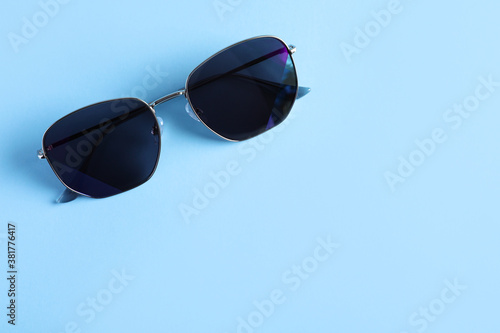 Stylish sunglasses on light blue background, top view. Space for text