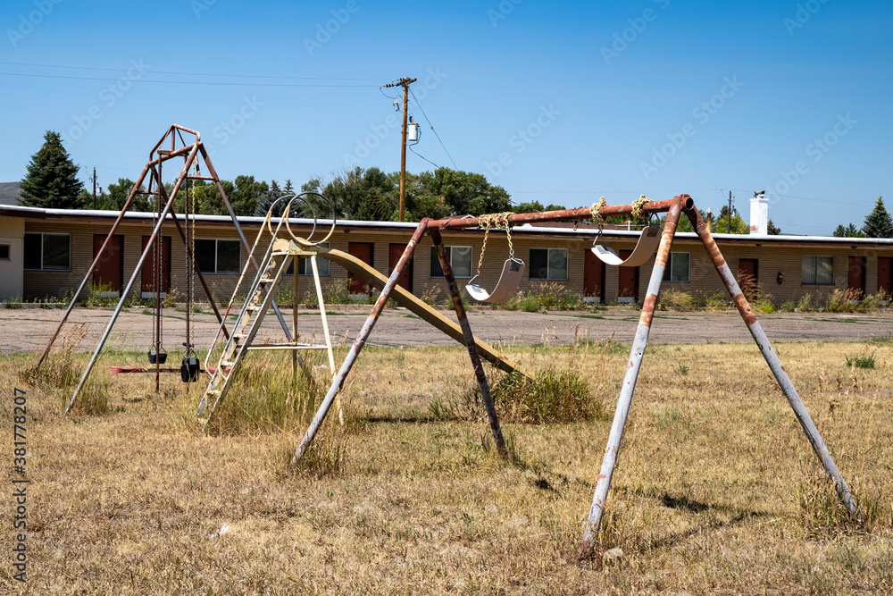 Rusty playground equipment with a swingset sits in a courtyard of an abandoned motel. Rusty playground equipment with a swingset sits in a courtyard of an abandoned motel.