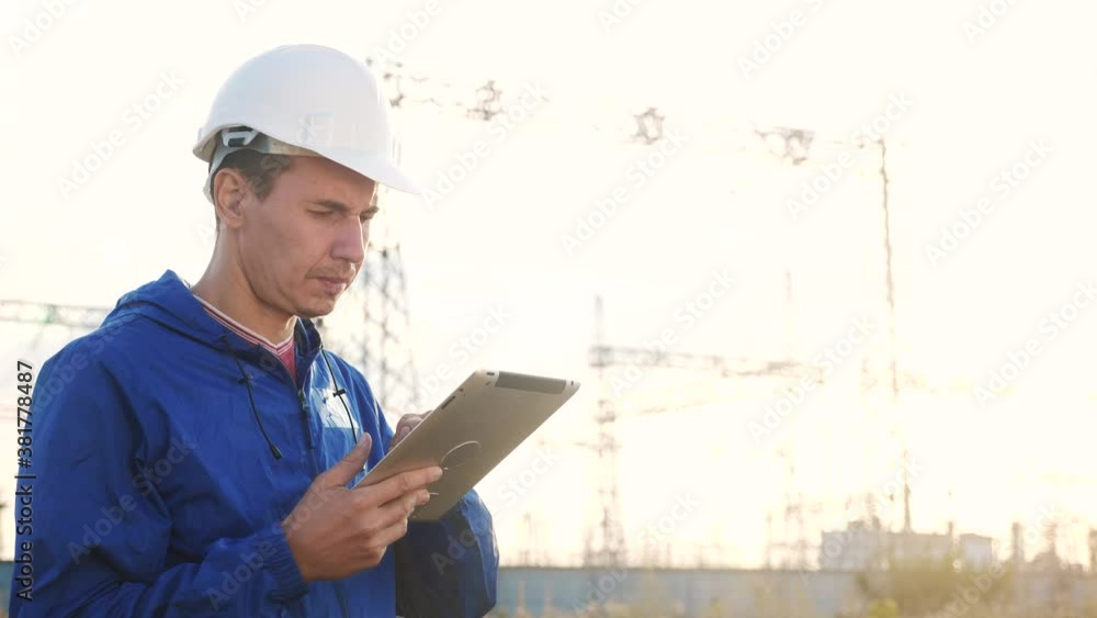 electrical worker engineer a working with digital tablet, near tower with electricity. business energy technology industry concept. electrical studying reading documents on power tablet electrical worker engineer a working with digital tablet, near tower with electricity. business energy technology industry concept. electrical studying reading documents on power tablet