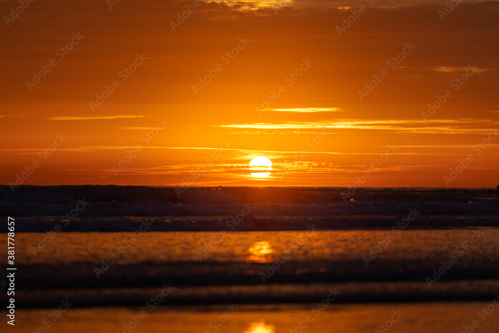 Silhouette-blurred background of beach during dramatic sunset with orange burning sky. High contrast and vibrant ratio photo.