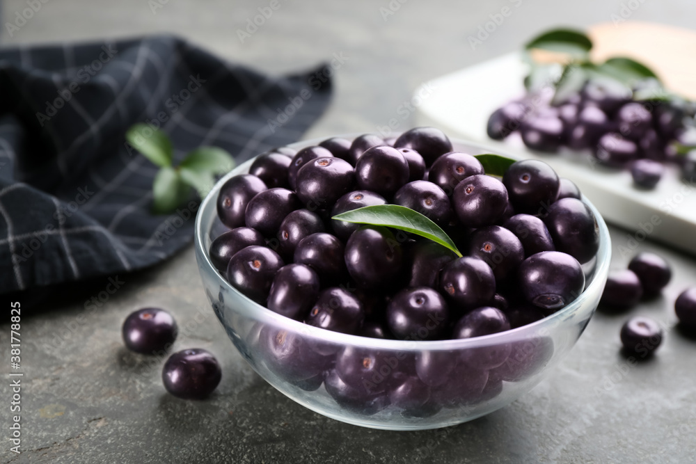 Fresh acai berries in glass bowl on grey table, closeup Fresh acai berries in glass bowl on grey table, closeup