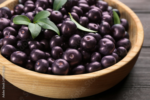 Tasty acai berries in wooden bowl on table, closeup