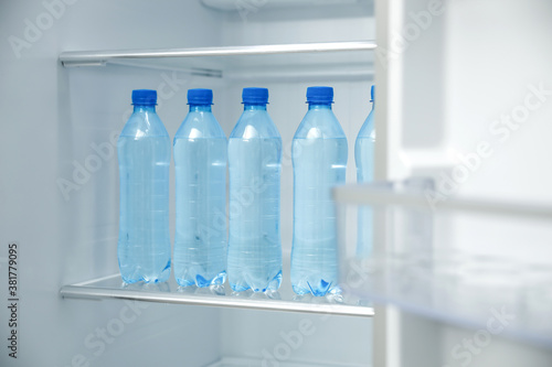 Many bottles with fresh water on fridge shelf