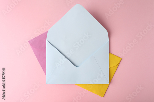 Colorful paper envelopes on pink background, top view