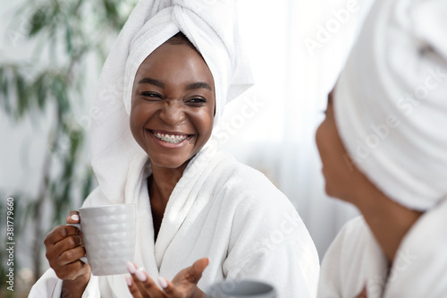Sticker Two young african women joking while drinking tea