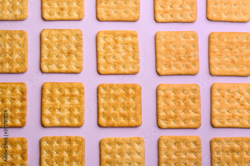 Delicious crackers on violet background, flat lay