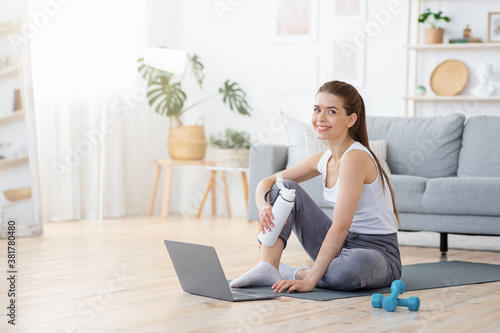 Smiling sporty woman resting on yoga mat