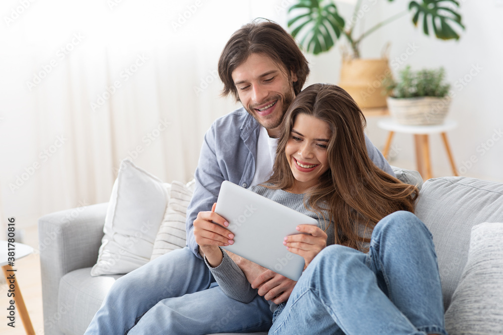 Positive young couple in love using digital tablet at home Positive young couple in love using digital tablet at home
