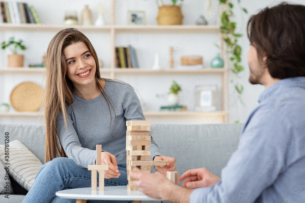 Cheerful couple in love playing Jenga at home Cheerful couple in love playing Jenga at home