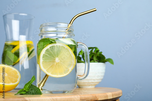 Refreshing water with cucumber, lemon and mint on wooden table. Space for text