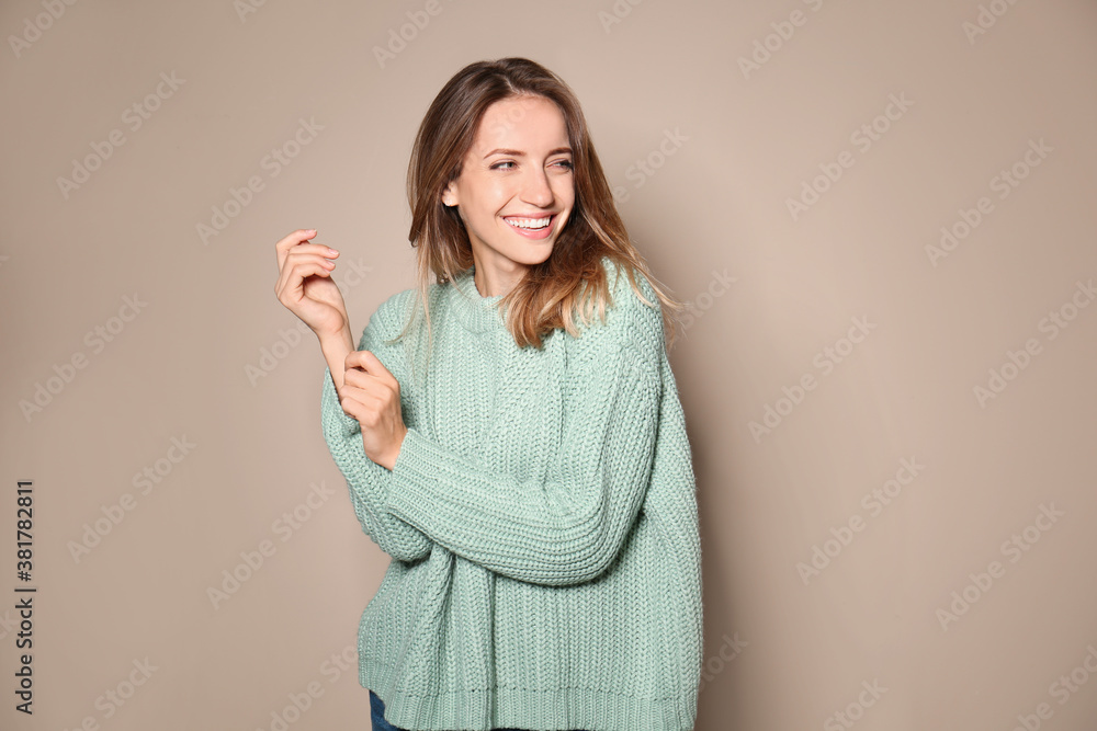 Happy young woman wearing warm sweater on beige background Happy young woman wearing warm sweater on beige background