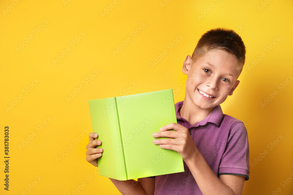 Happy little boy with book on yellow background Happy little boy with book on yellow background