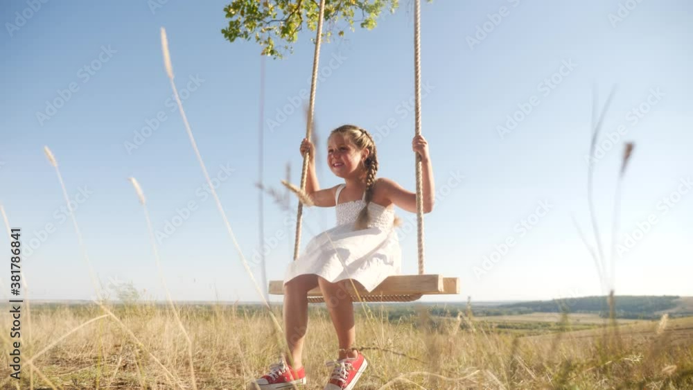 little girl kid swinging on wooden swing a tree in the park. happy family kid dream concept. little kid girl playing on wooden swing on tree dream concept in park. child a swing fun little girl kid swinging on wooden swing a tree in the park. happy family kid dream concept. little kid girl playing on wooden swing on tree dream concept in park. child a swing fun