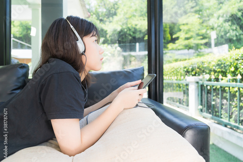 Wallpaper Mural Young girl listening to music from mobile phone in living room Torontodigital.ca