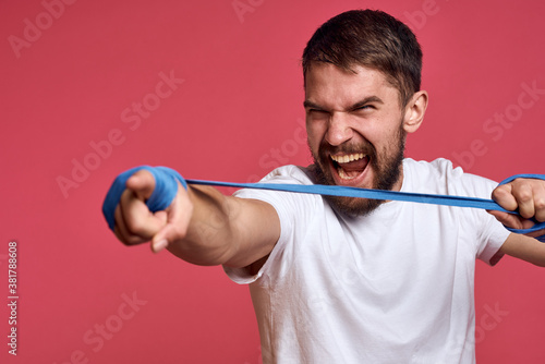 man in white t-shirt ties his hand with a bandage martial arts pink background