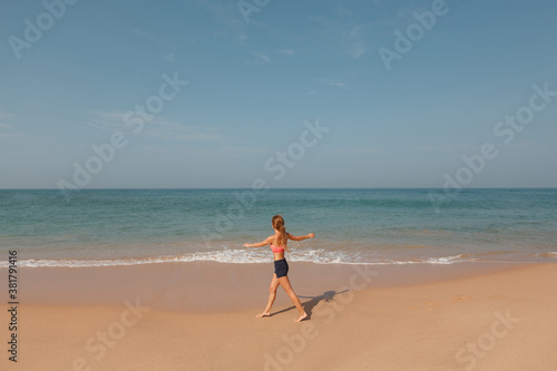 Sporty woman running by the sea on tropical beach during tropical vacation. Fitness and healthy lifestyle