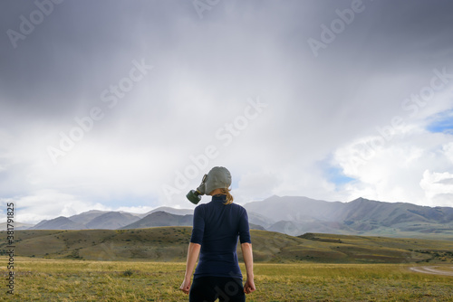 Risk of environmental disaster. Concept of pollution, apocalypse. Polluted air, ecological problems. Strong woman in military gas mask on the background of foggy mountains.