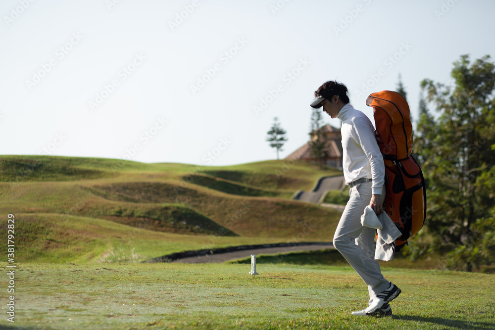 Golfers walking with golf club bags on the golf course.