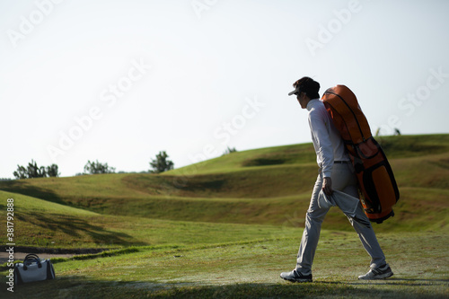 Golfers walking with golf club bags on the golf course.