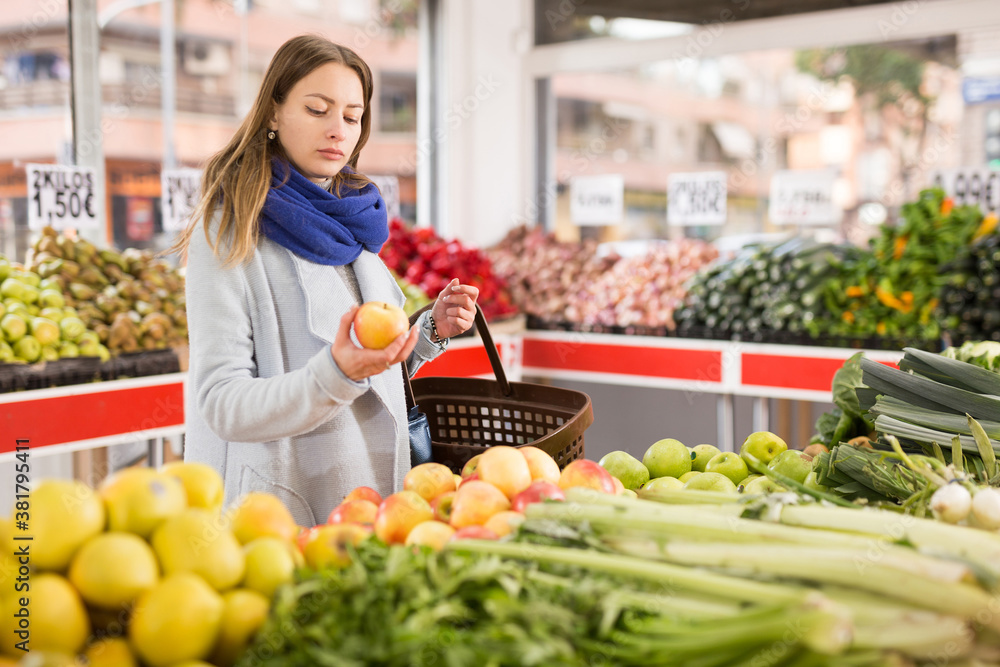 Woman is choosing fresh apples in grocery store. High quality photo