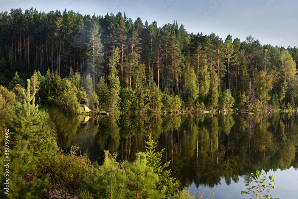 A beautiful view by the lake during sunset on a summer evening. Beautiful forest around