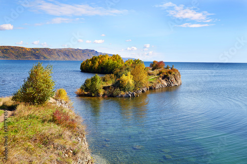 Autumn landscape with beautiful yellowed trees on the shore of lake Baikal on a sunny day. Shaman's Cape. photo