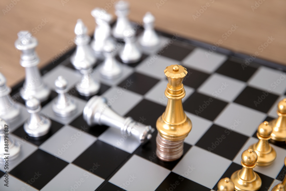 The silver queen pawn on the chess board kneels to the golden queen pawn standing on the coin The silver queen pawn on the chess board kneels to the golden queen pawn standing on the coin