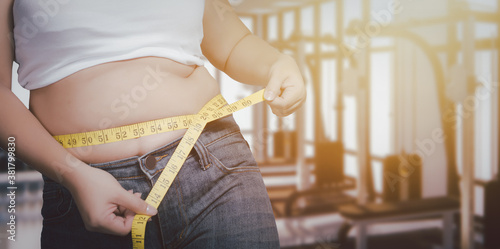 Fat woman,Woman body fat overweight squeeze tighten by measure tape or line tape .on fitness background.