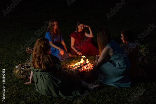 Lovely girls by the fire at night. Ancient pagan origin celebration concept. Night of Ivan Kupala. Ancient rituals.