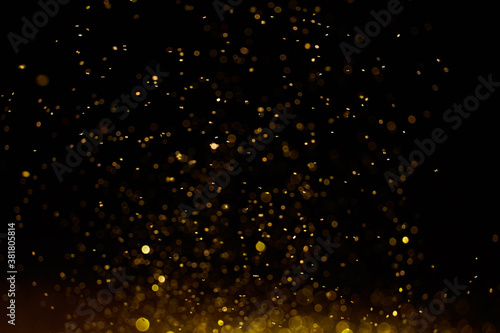 Sparkling golden glittering effect isolated on black background.