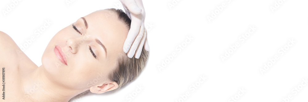 Girl lying in cosmetology spa. Face massage. Doctor hand with protective glove near head. Medical skin care. White background. Close eyes. Rejuvenation procedure. Cream cosmetics. Horizontal banner