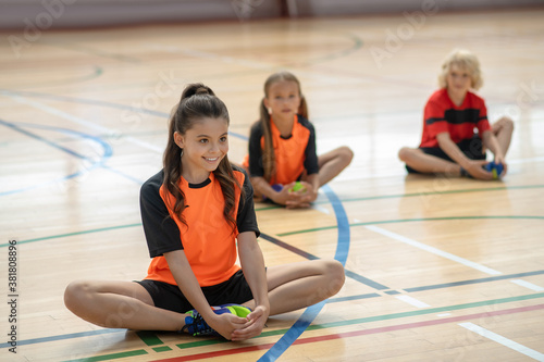 Three kids in bright sportswear stretching legs