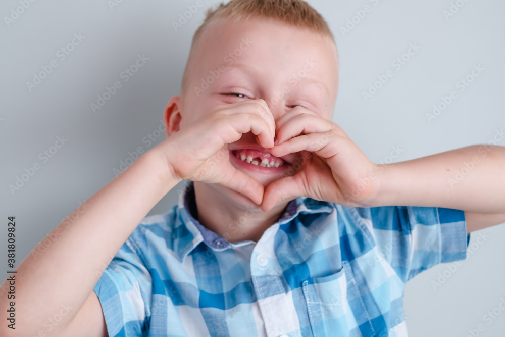 Close up image of smiling cheerful baby showing heart shape with hands.A hole in a child's smile. Cheerful concept.Health care, dental hygiene. High quality photo Close up image of smiling cheerful baby showing heart shape with hands.A hole in a child's smile. Cheerful concept.Health care, dental hygiene. High quality photo
